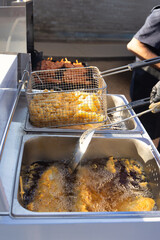 deep fried fish and chips cooking in a deep fryer , african man with a spoon turning the fish