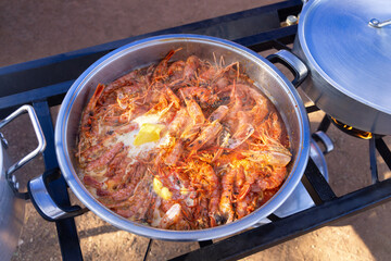 prawns with butter boiling in a pot cooking on gas stove outdoors