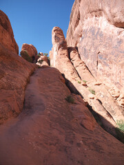Climbing on massive red rock cliff in Arches National Park, Utah