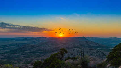 Birds flying in front of the sun at sunset atop Mount Scott, near Medicine Park, Oklahoma. © Lee