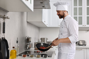 Professional chef cooking delicious food in frying pan indoors