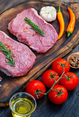 Vertical Raw meat beef steak organic fresh ingredient on wooden board table background in kitchen with rosemary salt garlic tomato black pepper olive oil. Vertical Meat beef wooden plate beefsteak