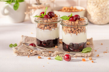 Healthy and homemade cherries granola in jar with yoghurt.