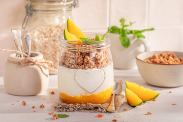 Delicious and homemade mango granola in jar with oat flakes.