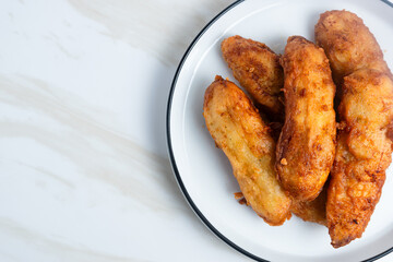 Fried Banana served on a white plate. Indonesian food. Indonesian street food. Perfect for recipe, article, catalogue, commercial, or any cooking contents.