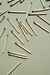 Wooden matchsticks with green tips scattered on light green surface.