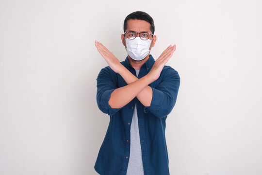 A man wearing medical face mask doing stop hand sign