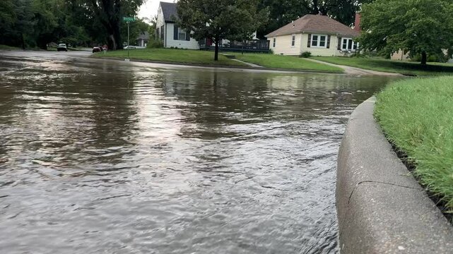 A low angle view of flowing deep flood water after heavy rains in a historic neighborhood in the midwest - flooding in the suburbs