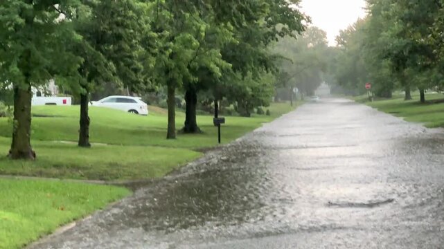 Flood water overwhelms city drainage systems, flooding the street after heavy rains. Drainage and water in historic neighborhood in the midwest - flooding in the suburbs due to severe weather events.