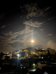 view of the big, full moon and clear sky above the city at night