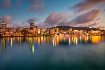 Downtown Wellington New Zealand, central city buildings reflected in the harbour at sunrise with a blue sky and warm toned clouds.