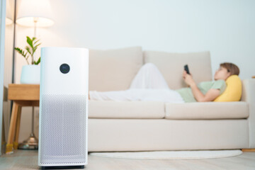 Air Purifier with woman relax and use smartphone on sofa. Purification system for filter and...