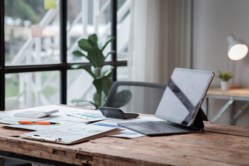 Laptop Computer, notebook, and eyeglasses sitting on a desk in a large open plan office space after working hours	