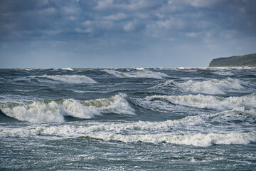 Dramatic ocean waves crashing against the shore under a cloudy sky