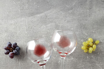 Glasses with wine and grapes, on a gray background.