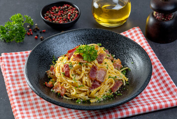 Spaghetti Carbonara in black plate on black table background