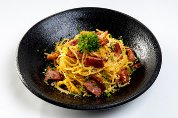 Spaghetti Carbonara in black plate on white background