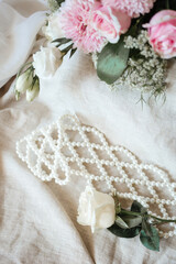 White beads with roses on linen fabric top view. The concept of a wedding and a romantic date