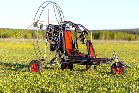 Paragliding machine for paragliding flights on green grass against the bright sun. Preparing paralet with a gasoline engine for flights. Extreme sports