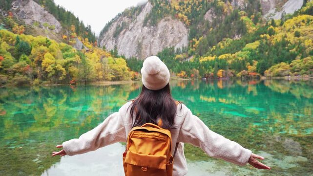 Young female tourist looking at beautiful autumn scenery landscape at jiuzhaigou national park in Sichuan, China