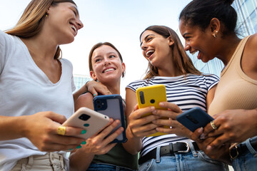 Low angle view of happy multiracial group of young women friends laughing and having fun while...