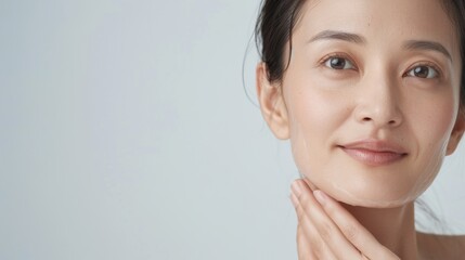 Beautiful asian woman with clean fresh skin on white background, hand on face.