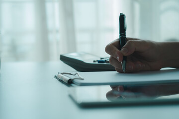 Obraz premium Working home concept .Person writing clipboard desk with tablet documents in bright office atmosphere, planning business tasks, taking financial notes planning taxes, calculating investment income.