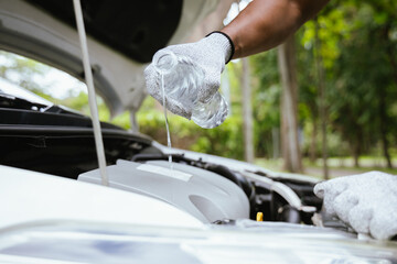 A technician in a workshop uses a wireless device to check a car's condition, updating a digital...