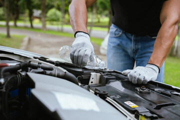 Obraz premium A technician in a workshop uses a wireless device to check a car's condition, updating a digital certificate. The scene highlights automotive repair, service, and efficiency in maintenance.