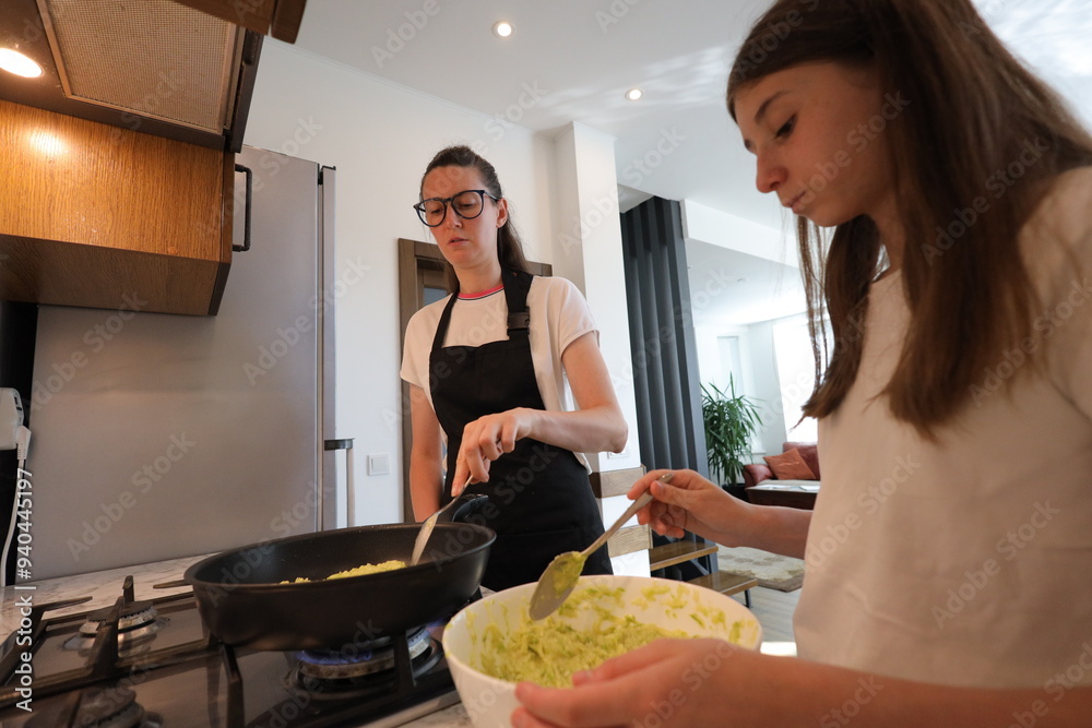 Wall mural Mother and daughter cooking food at home in the kitchen