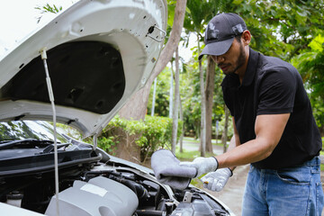 A technician examines a car engine in a garage, focusing on battery and electrical components. The...