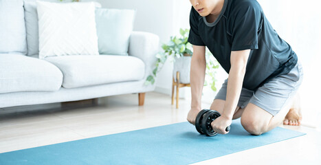 腹筋ローラーを使いトレーニングをする男性