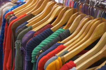 Various colorful garments beautifully arranged on wooden hangers inside a boutique shop