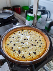 sweet pancake or martabak dough cooked on a griddle with raisin topping