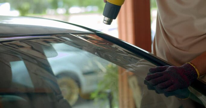 The film installer uses a hot gun to blow the film into the shape of the glass before installing it.Car tint technicians are replacing the film with a new one that better protects against UV light.