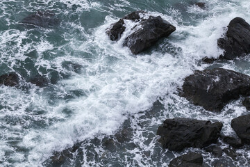 Black coastal rocks and shore water, aerial view. Dongbaek Park of Busan
