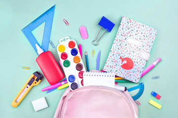 Back to school concept. School supplies are collected in a backpack. Pastel colors flat lay