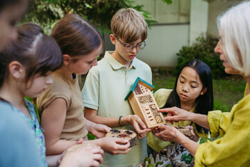 Insect hotel as educational tool for children in outdoor sustainable educational class. Young students learning about insect and biodiversity.