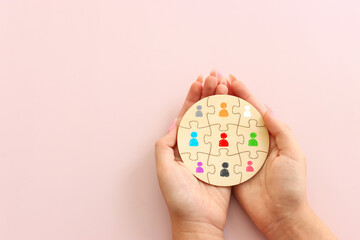 Business image of puzzle with people icons over pastel background, human resources and management concept