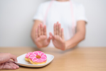 woman hand reject donut dessert, female refuse Unhealthy junk food. Dieting control, Weight loss,...