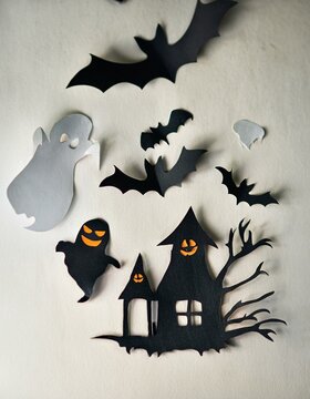 Playful ghosts and bats flutter around a spooky house, its glowing windows casting an eerie light. Perfect for Halloween crafts, this image captures the essence of a fun and festive atmosphere.