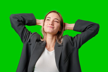 Woman in Black Blazer Leans Back With Hands Behind Head Against Green Screen