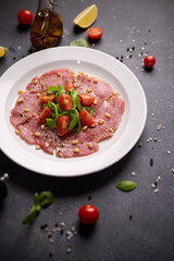 cooking tuna carpaccio - Fresh raw tuna fillet with olive oil and pine nuts on white ceramic plate
