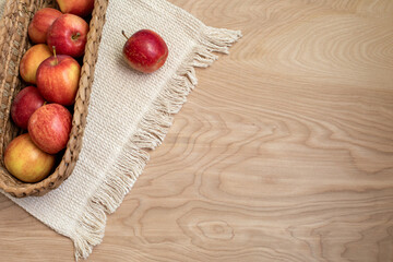 Top view on a woven long basket with red and yellow gala apples on wooden surface with copy space