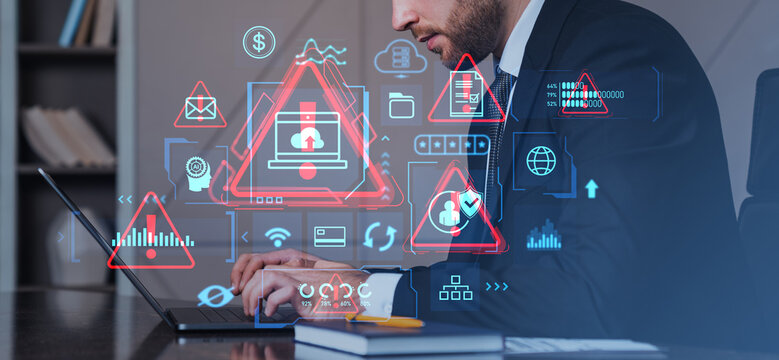 Cybersecurity analyst working on laptop with digital warning ico