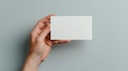 Fototapeta premium A hand confidently holds a blank card, ready for customization in a mockup for product presentations or advertisements, with ample space for text