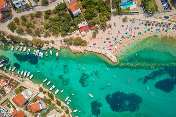 Aerial top view of coastal village with red-roofed houses, turquoise waters and boats along shore. Panorama of tourist town Rogoznica in Croatia on Adriatic Sea. Summer vacation concept