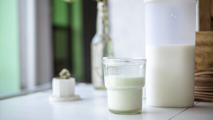 White milk in a glass with blurred background of ornamental plants