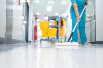 A cleaner in uniform using mops cleaning hall floor at patient room the hospital epoxy floor.