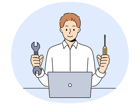 Man repairs laptop after breakdown and holds screwdriver and wrench in hands, working as system administrator. Guy fixes laptop or wants to upgrade by replacing hard drive of computer